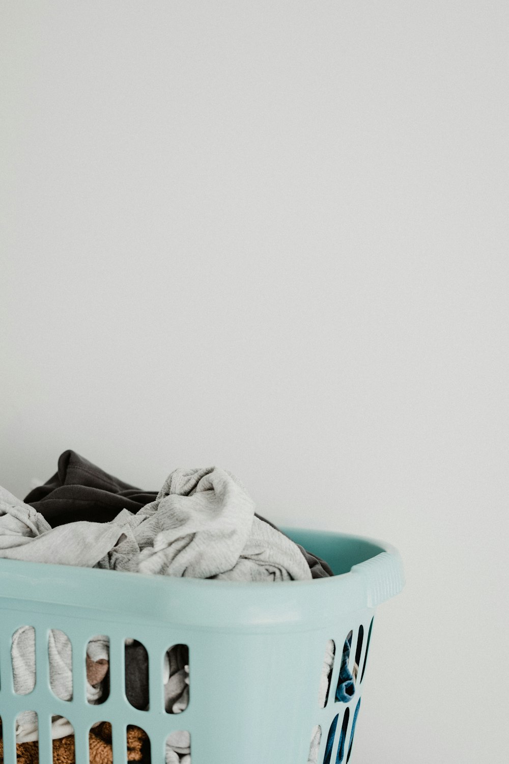 Canasto azul con ropa junto a una lavadora