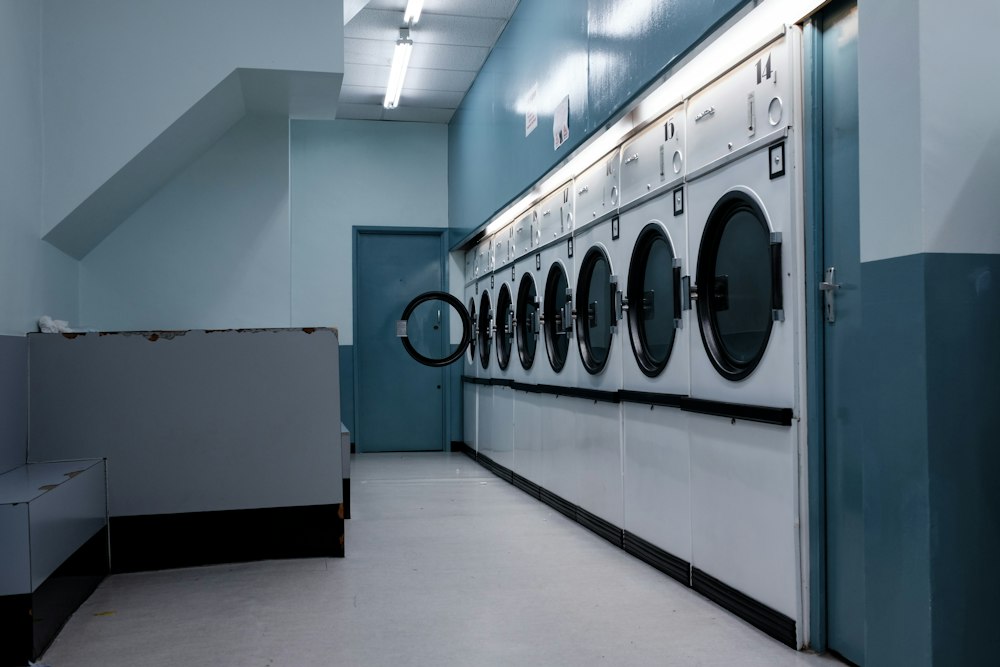 Fila de lavadoras de carga frontal en una sala de muros azules